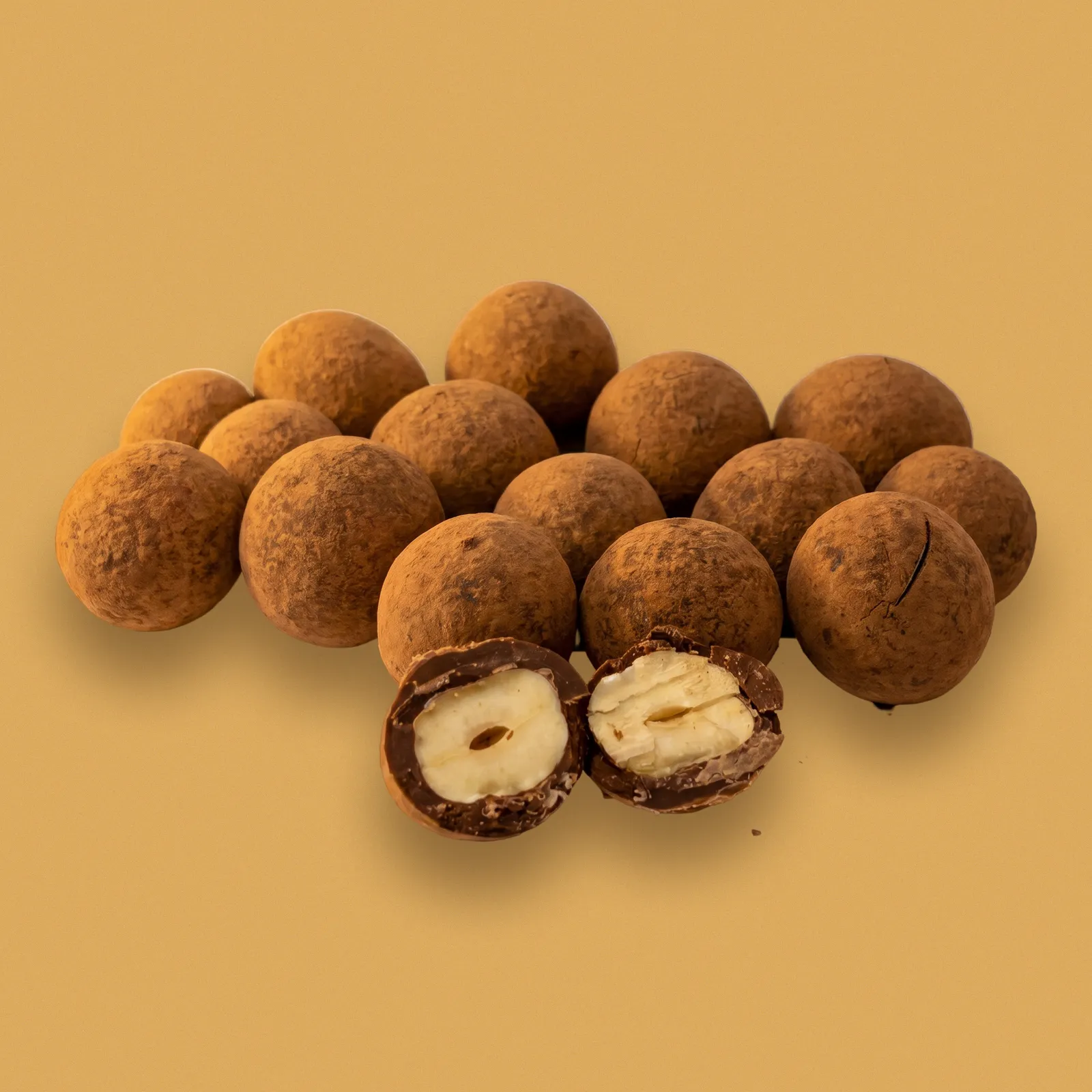 Drageados de avelã empilhados; um cortado ao meio mostra as camadas de chocolate sobre a avelã inteira